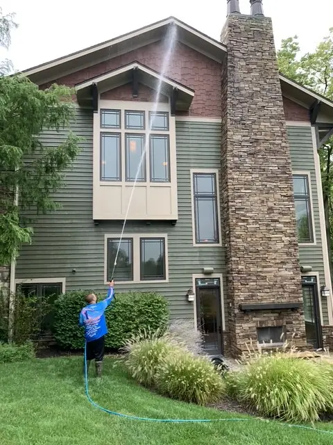 House washing on a green siding home with stone chimney in Fort Thomas, KY