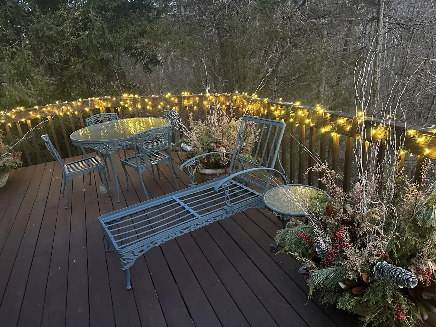 Deck railing wrapped in Christmas lights with garland and winter planters in Mariemont, OH