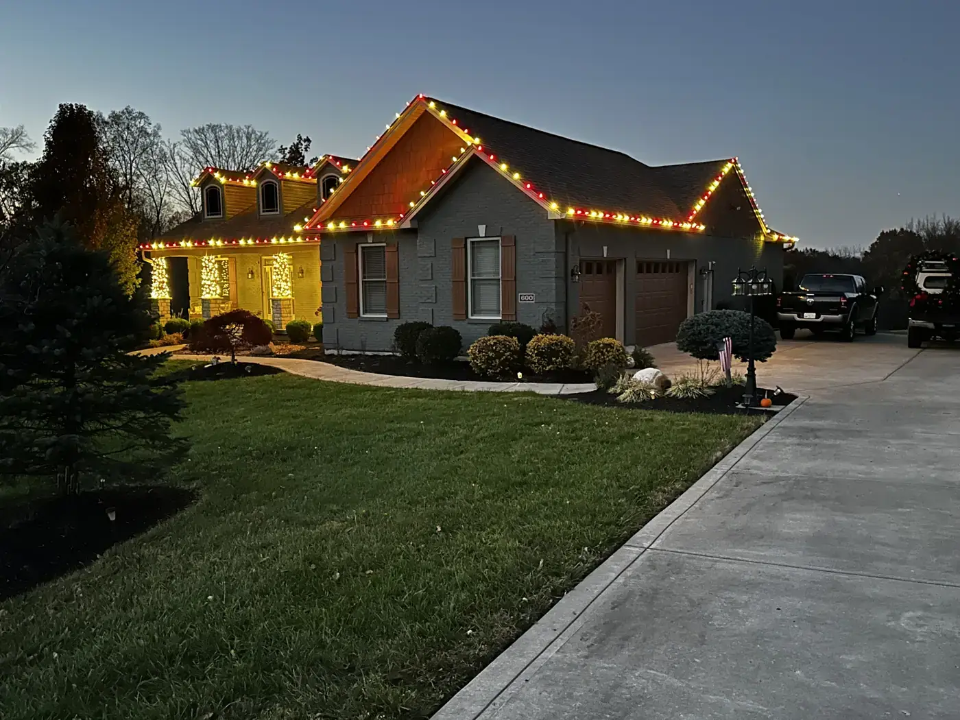 Christmas Light Installation in Edgewood, KY Red and warm white Christmas roofline lights with lit porch columns on a brick ranch home