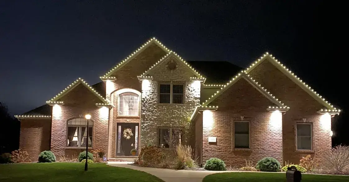 Christmas roofline lights on a stone home with an arched front window in Mariemont, OH