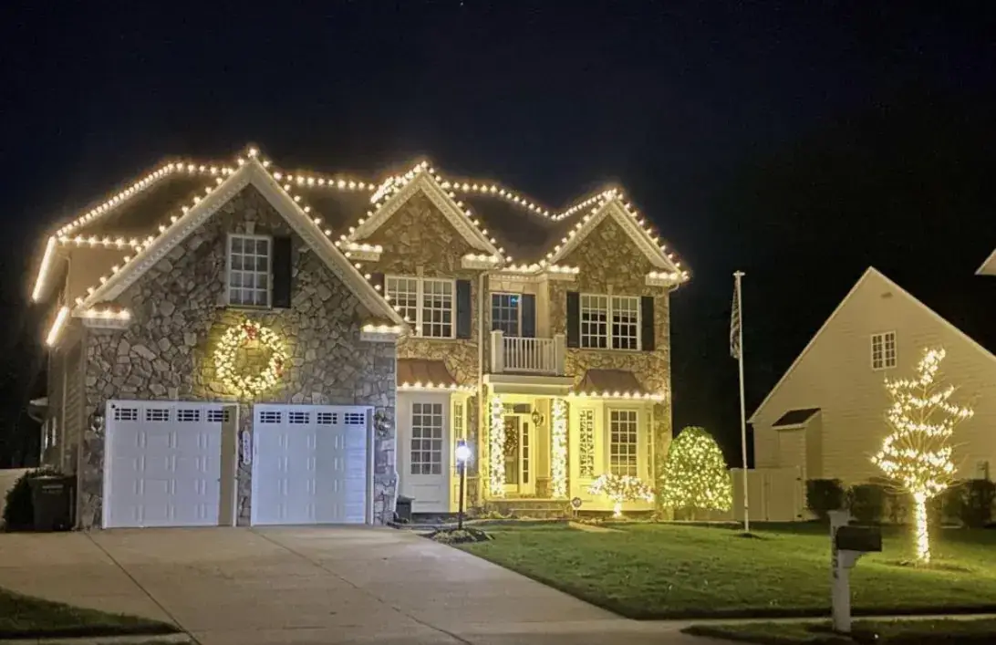 Christmas Light Installation in Indian Hill, OH Christmas roofline lights, wreath and wrapped tree at a stone two-story home in Indian Hill, OH