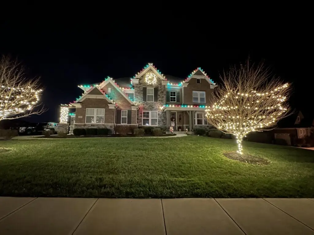 Christmas Lighting Red, green and white Christmas lights on a brick home with wrapped trees
