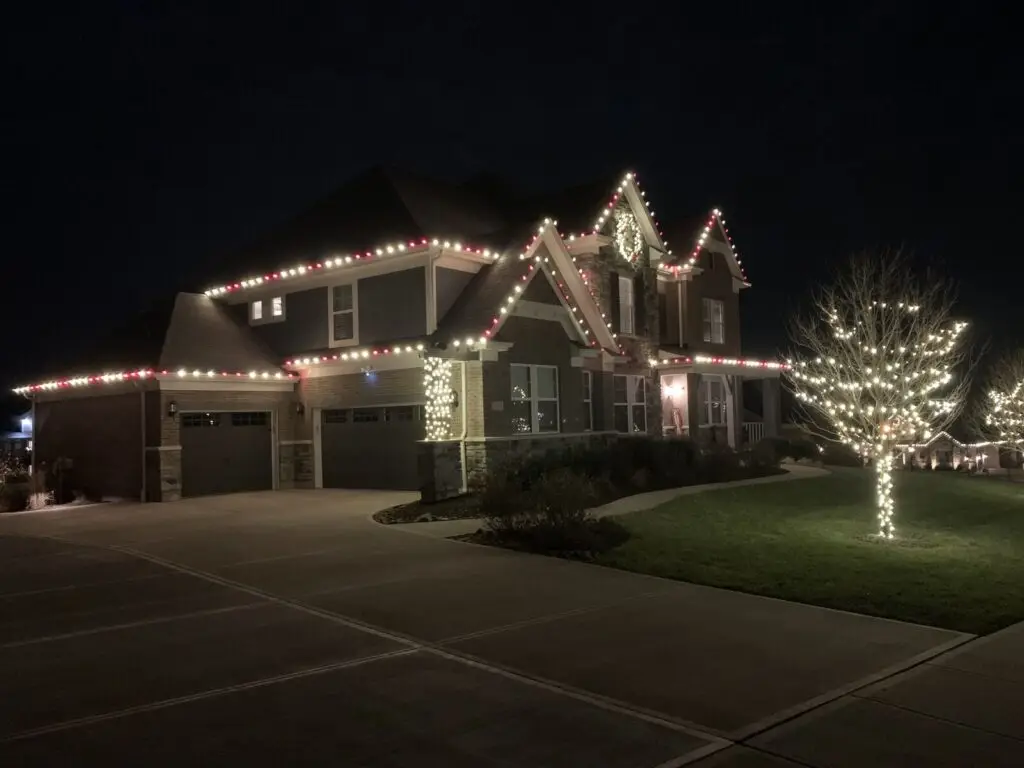 Christmas Lighting Red and white Christmas lights on a two-story home with a lighted front yard tree